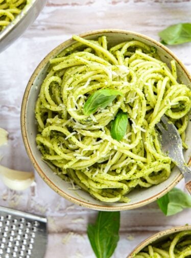 bowl with pesto pasta garnished with fresh basil Parmigiano-Reggiano