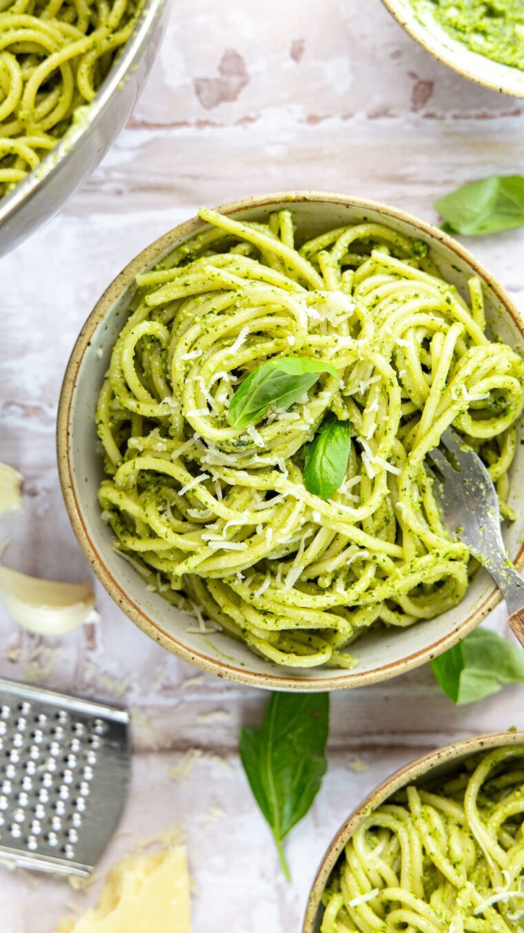 bowl with pesto pasta garnished with fresh basil Parmigiano-Reggiano