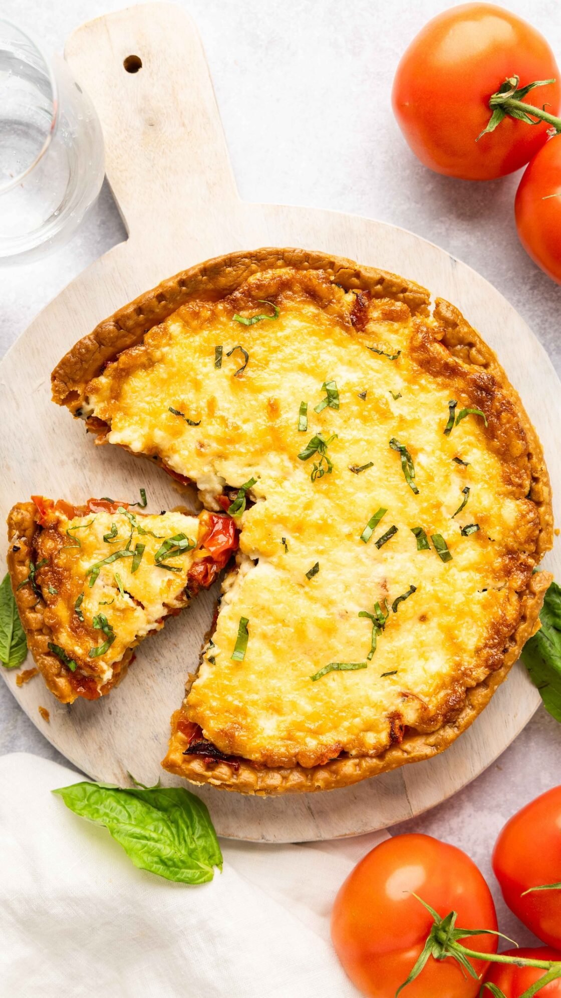 southern tomato pie on platter with tomatoes on the table