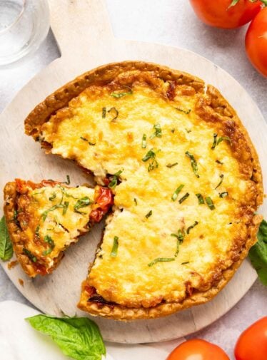 southern tomato pie on platter with tomatoes on the table