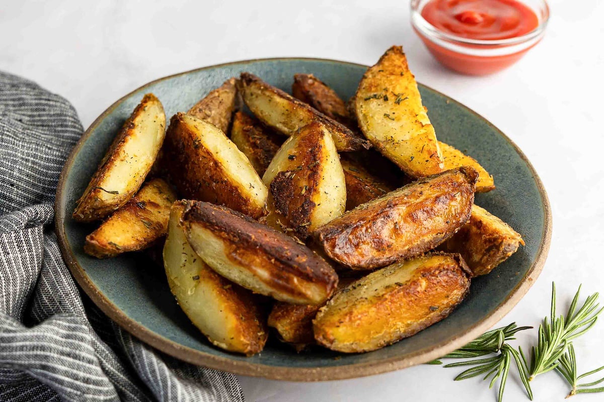 crispy baked potato wedges in gray bowl with side of ketchup
