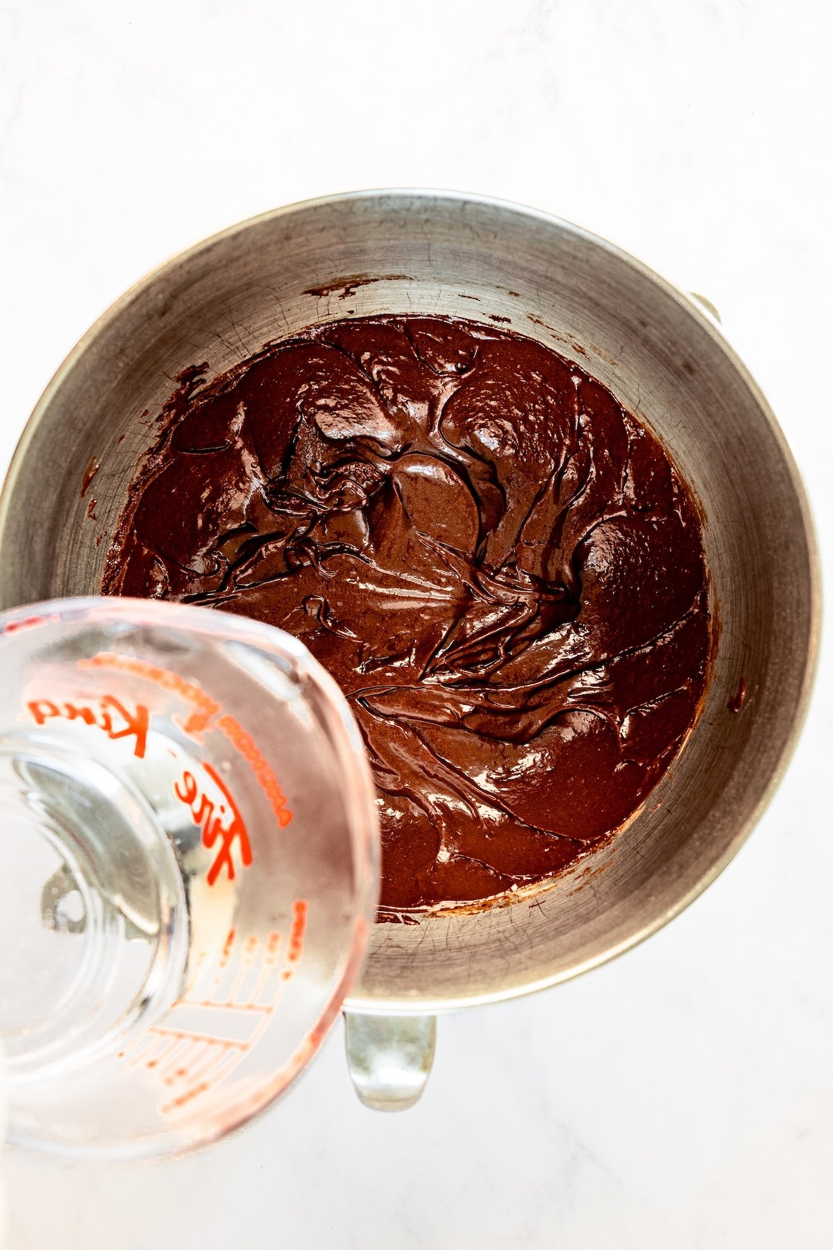 water being added to cake batter in mixing bowl