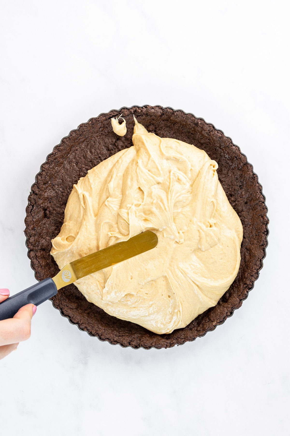 offset spatula spreading peanut butter/whipped cream filling in pie crust