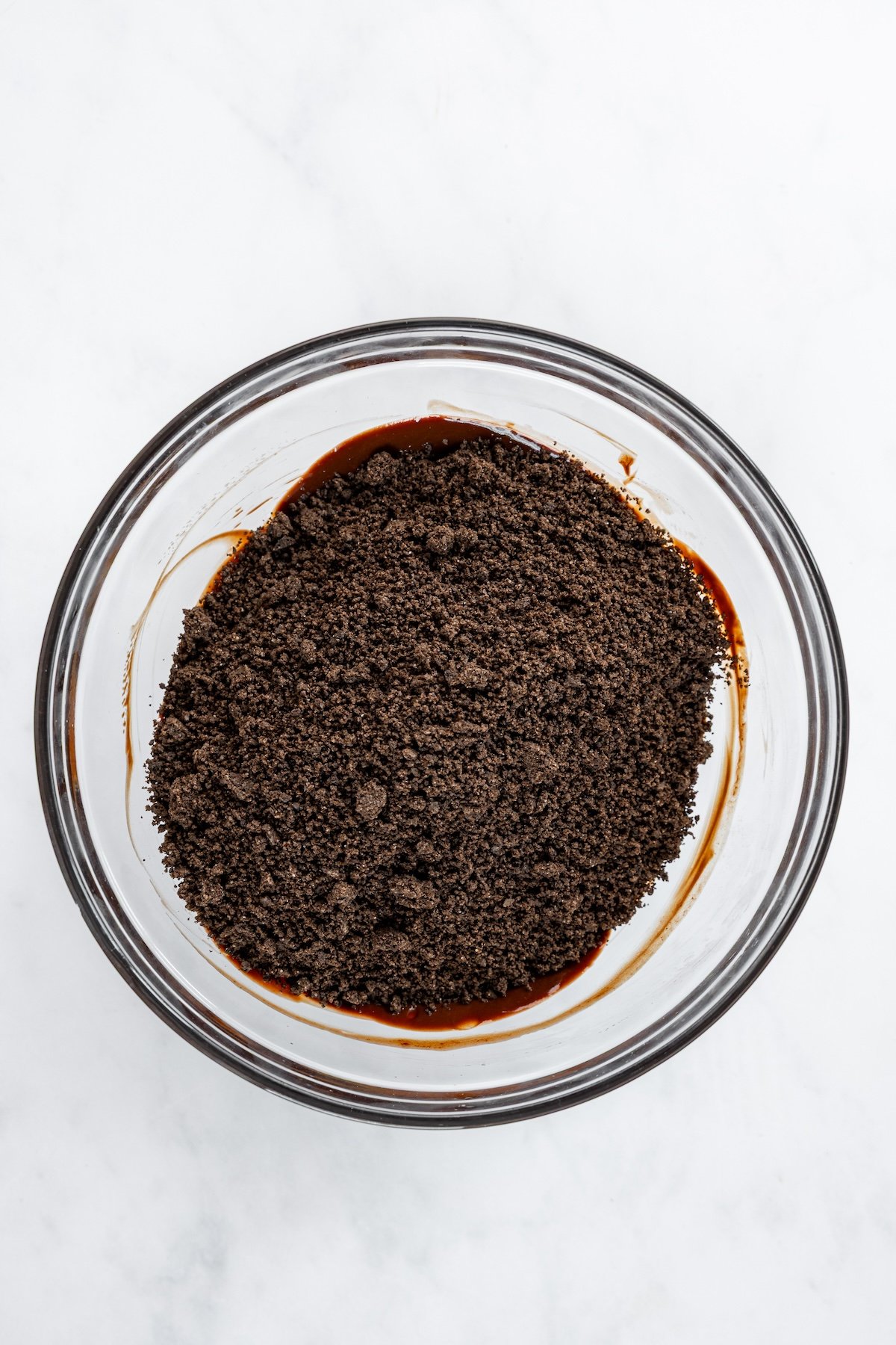 medium bowl with cookie crumbs on top of chocolate/butter mixture
