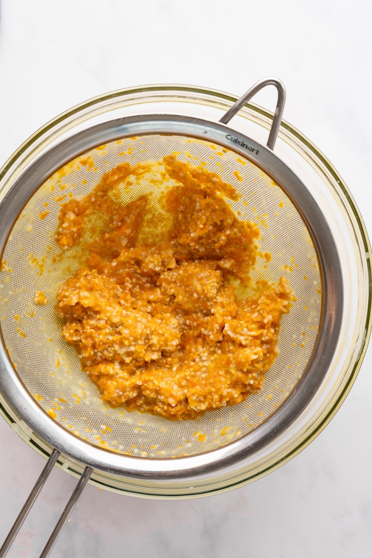 yellow tomato seeds and skins in a strainer