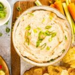 Sun-dried tomato dip in serving bowl on wood cutting board
