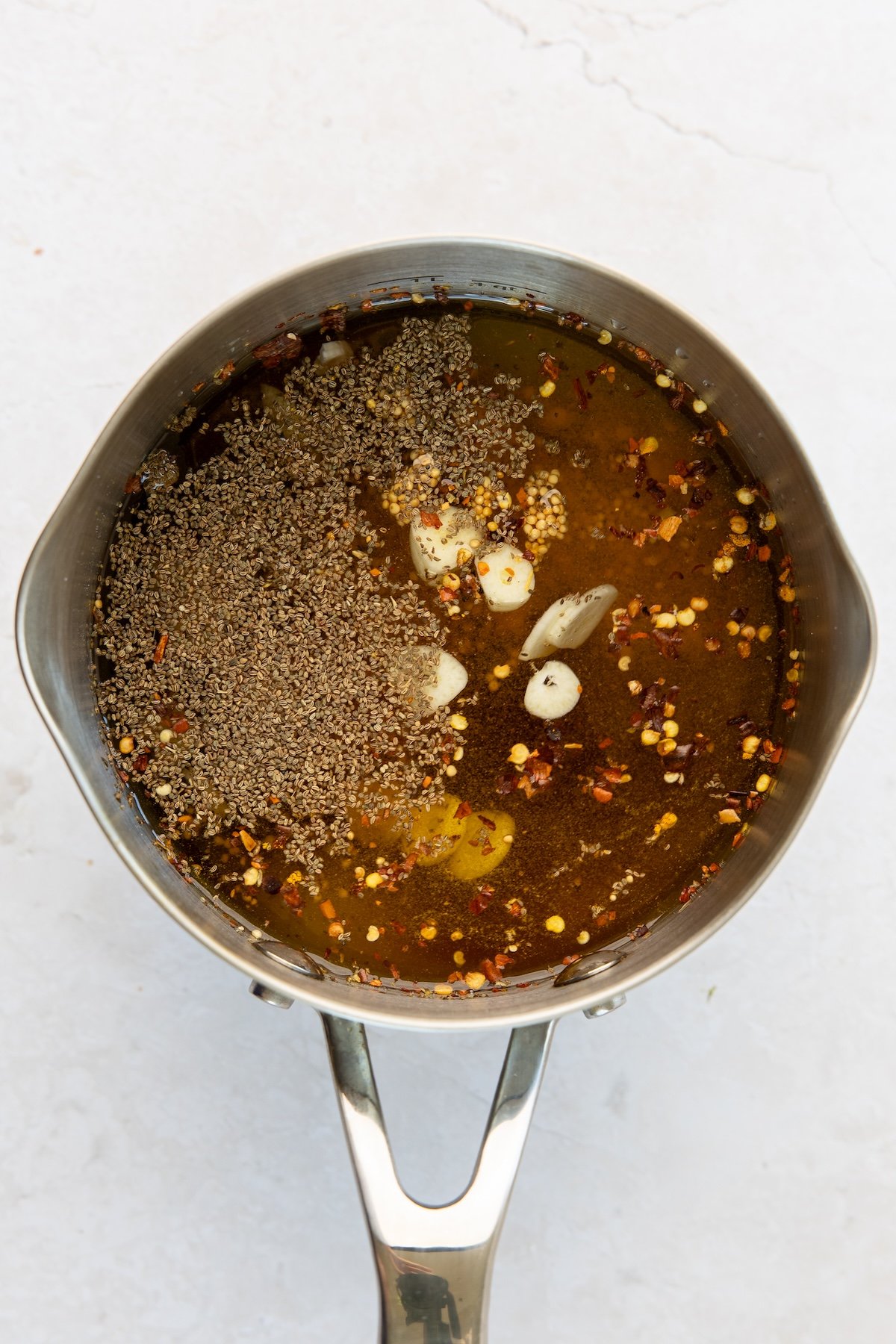 medium saucepan with vinegar, granulated sugar, brown sugar, garlic, mustard seeds, celery seeds, turmeric, cloves, and red pepper flakes