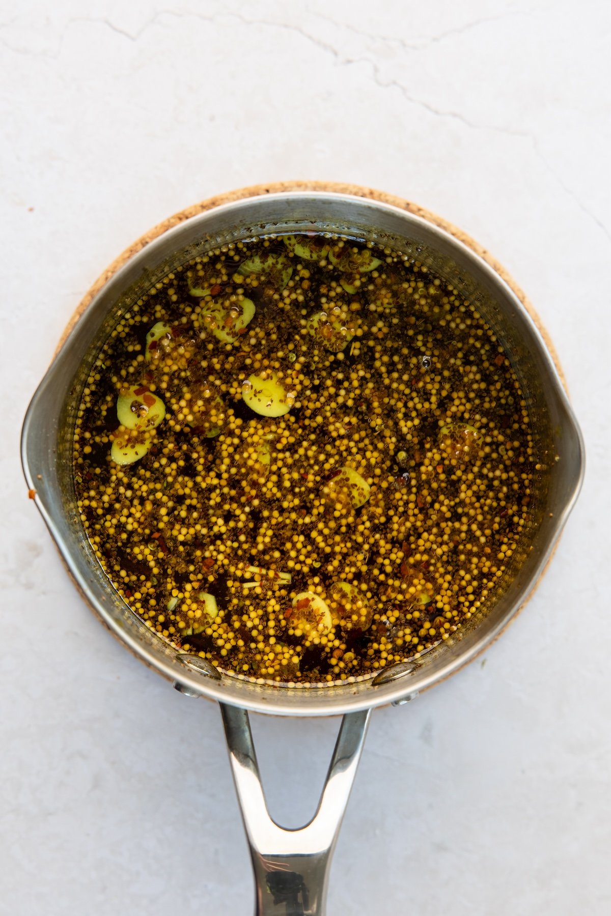 medium saucepan with simmered vinegar, granulated sugar, brown sugar, garlic, mustard seeds, celery seeds, turmeric, cloves, and red pepper flakes
