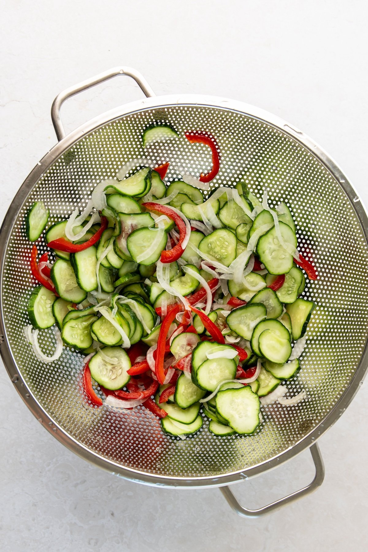 cucumbers, onions, and bell pepper in colander
