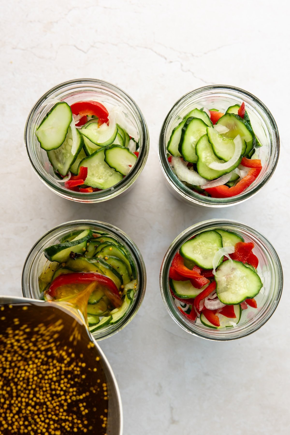cucumber, onion and red pepper divided into four 1-pint jars