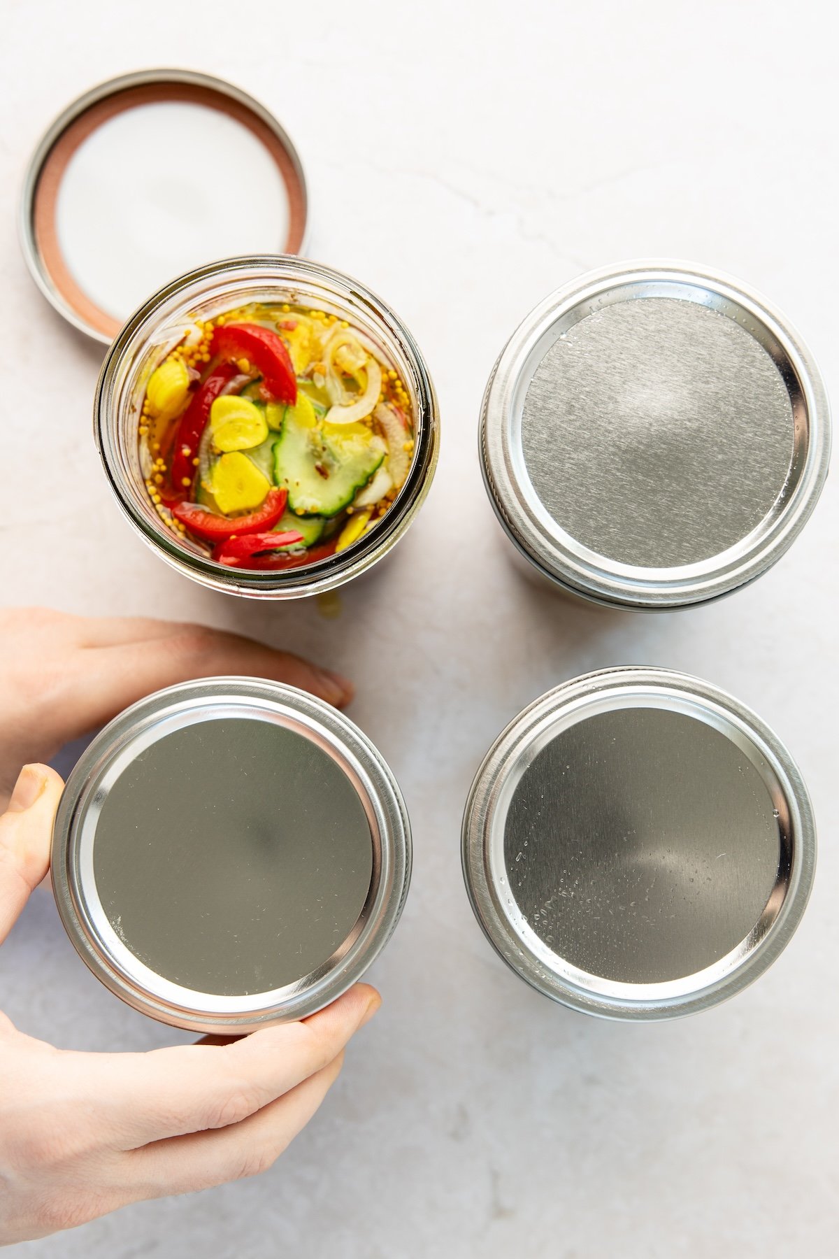 cucumbers, onions, and peppers submerged in brine with jar tops screwed on