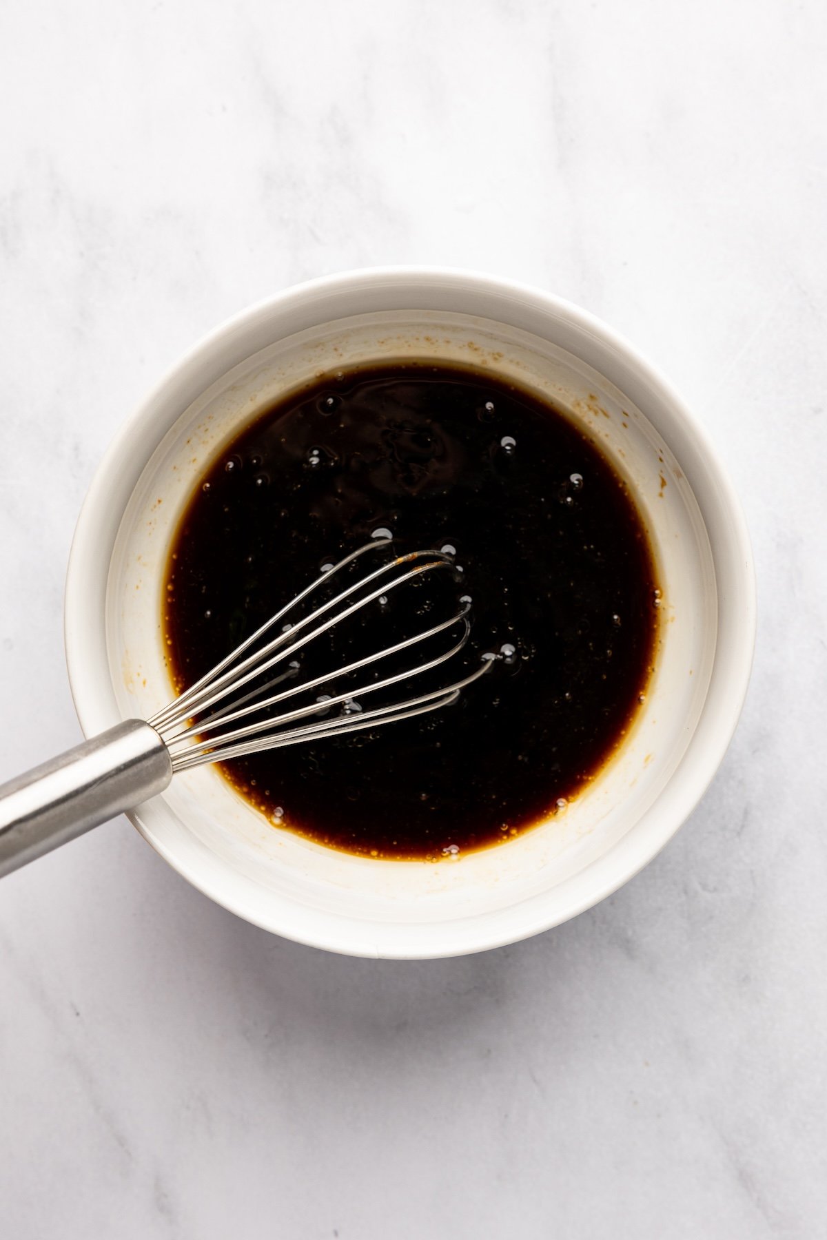 sauce mixture in white bowl with whisk