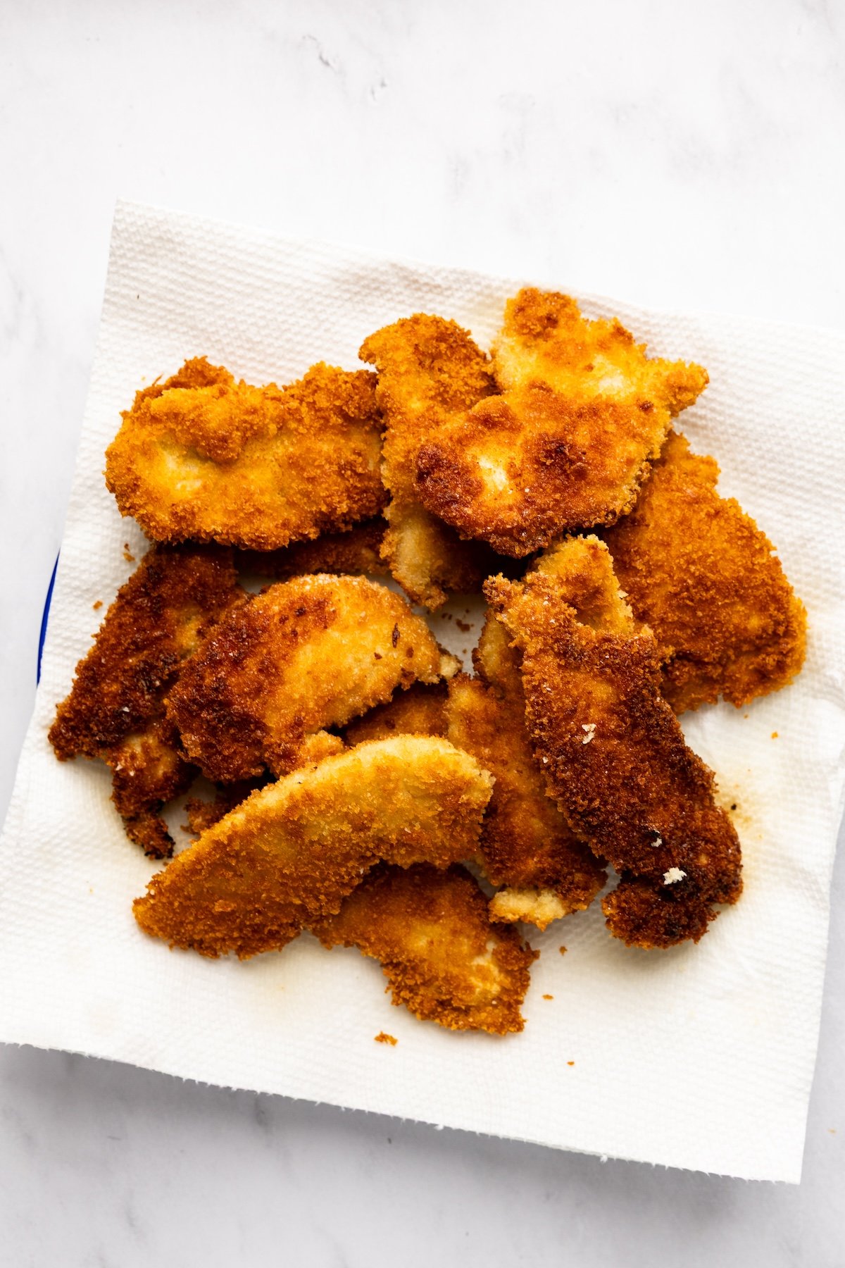 draining chicken on a paper towel-lined plate