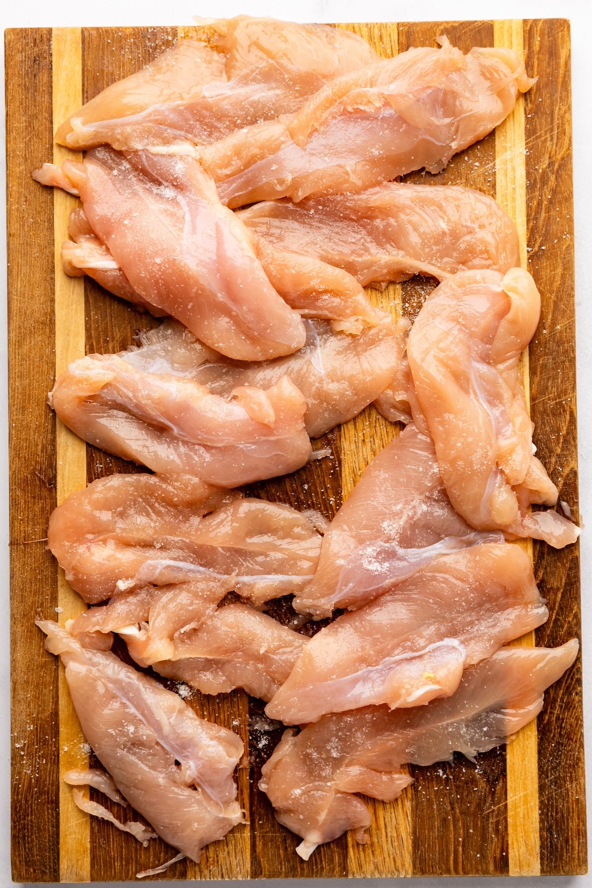 chicken tenderloins seasoned on cutting board