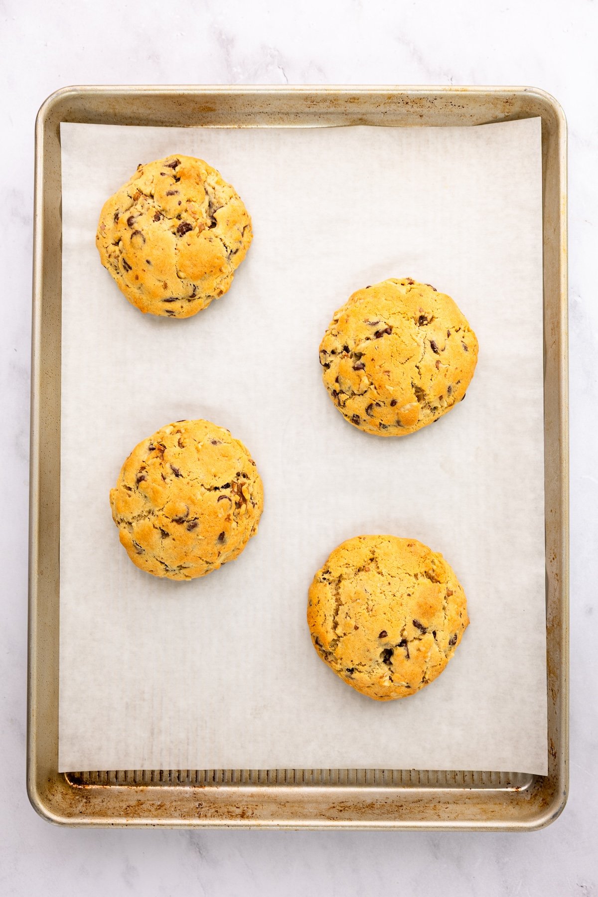 parchment-lined baking sheet with 4 baked cookies