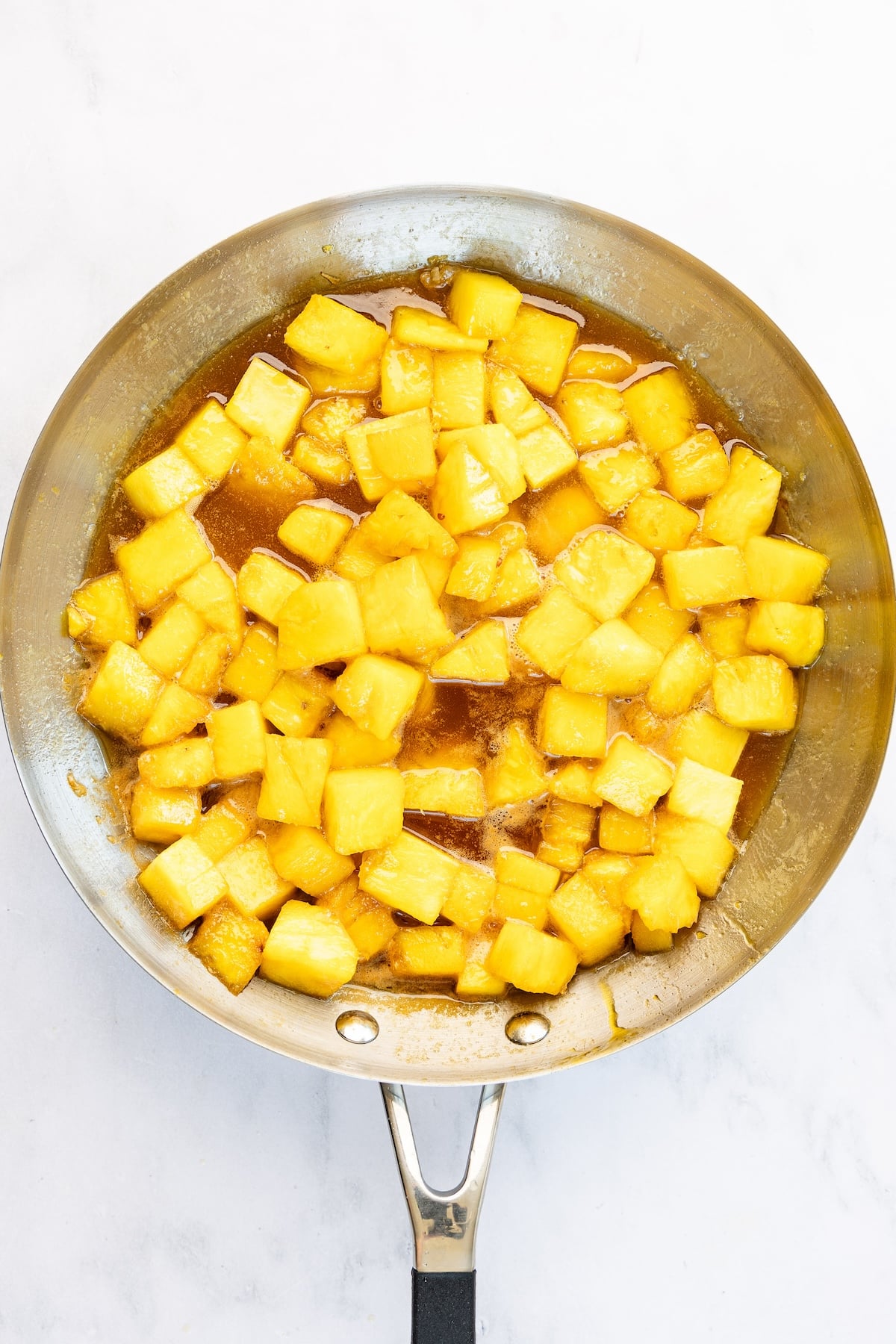 12-inch skillet with softened pineapple chunks in caramel mixture