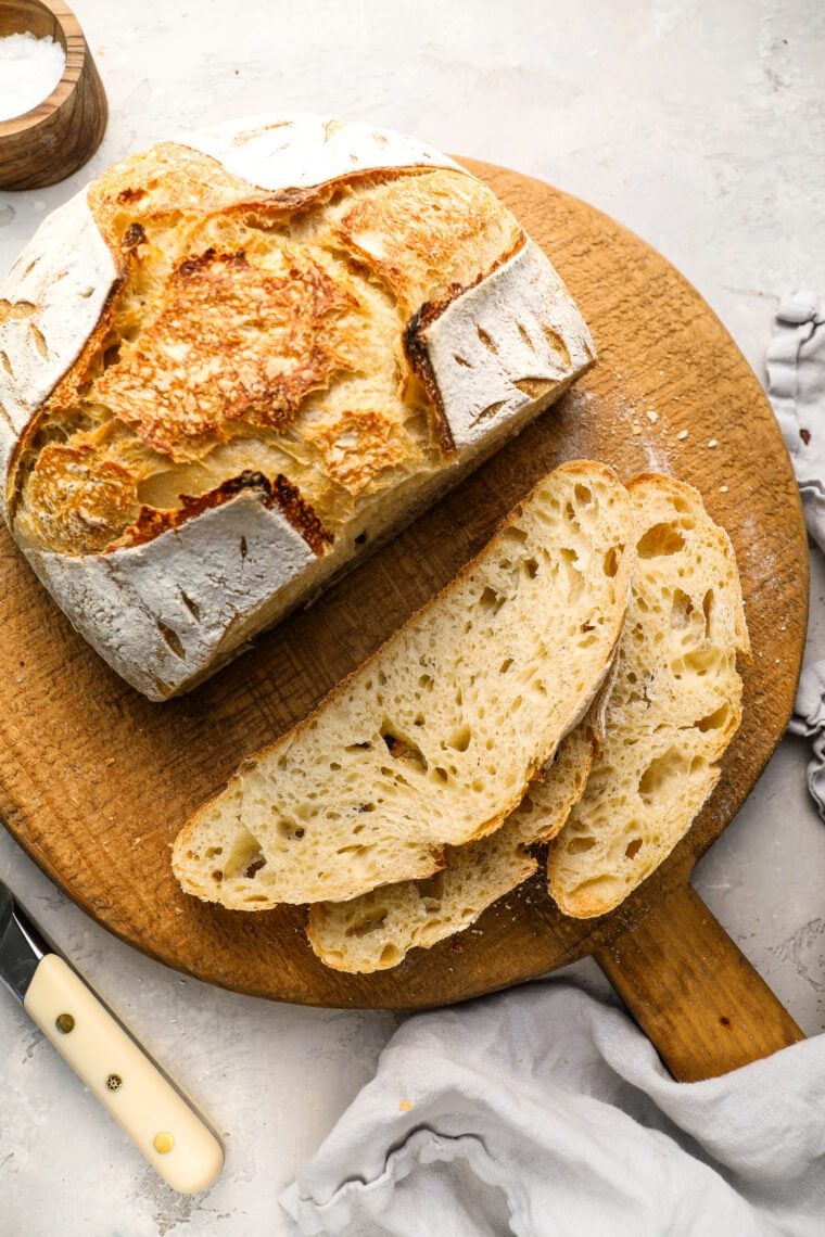 slices of sourdough bread laying next to remainder of loaf