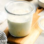 Démarreur au levain dans un pot posé sur une planche à découper