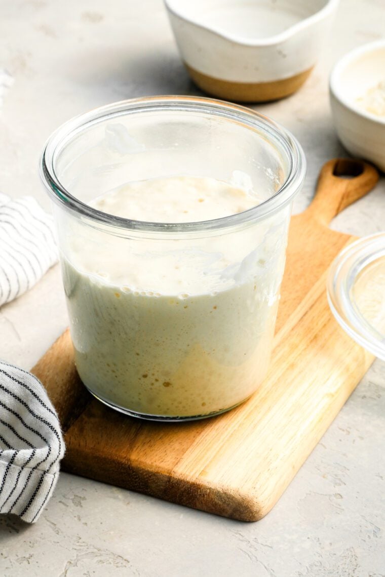 sourdough starter in a jar sitting on a cutting board