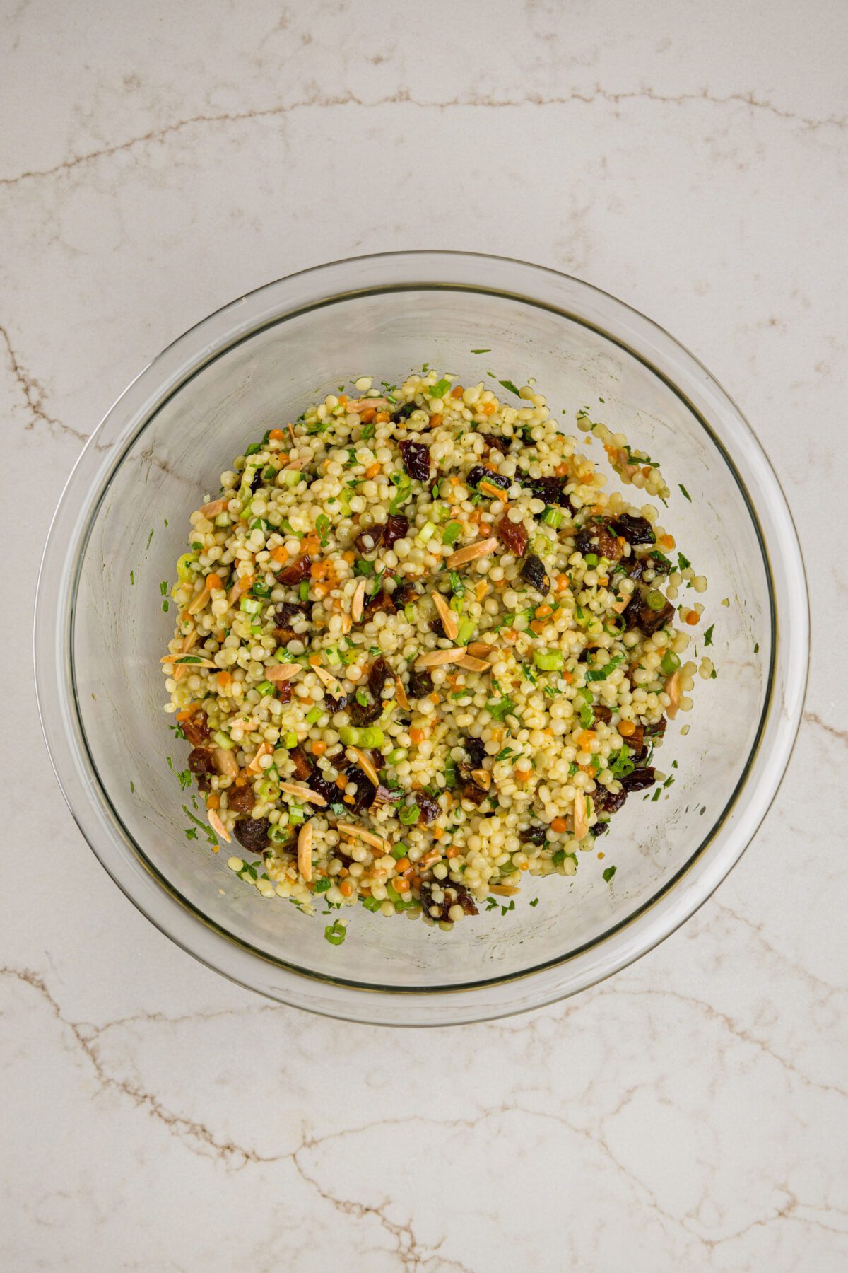 tossed israeli couscous salad in mixing bowl