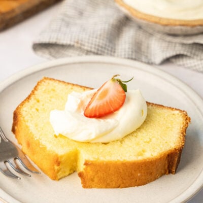 slice of cream cheese pound cake topped with whipped cream and strawberries