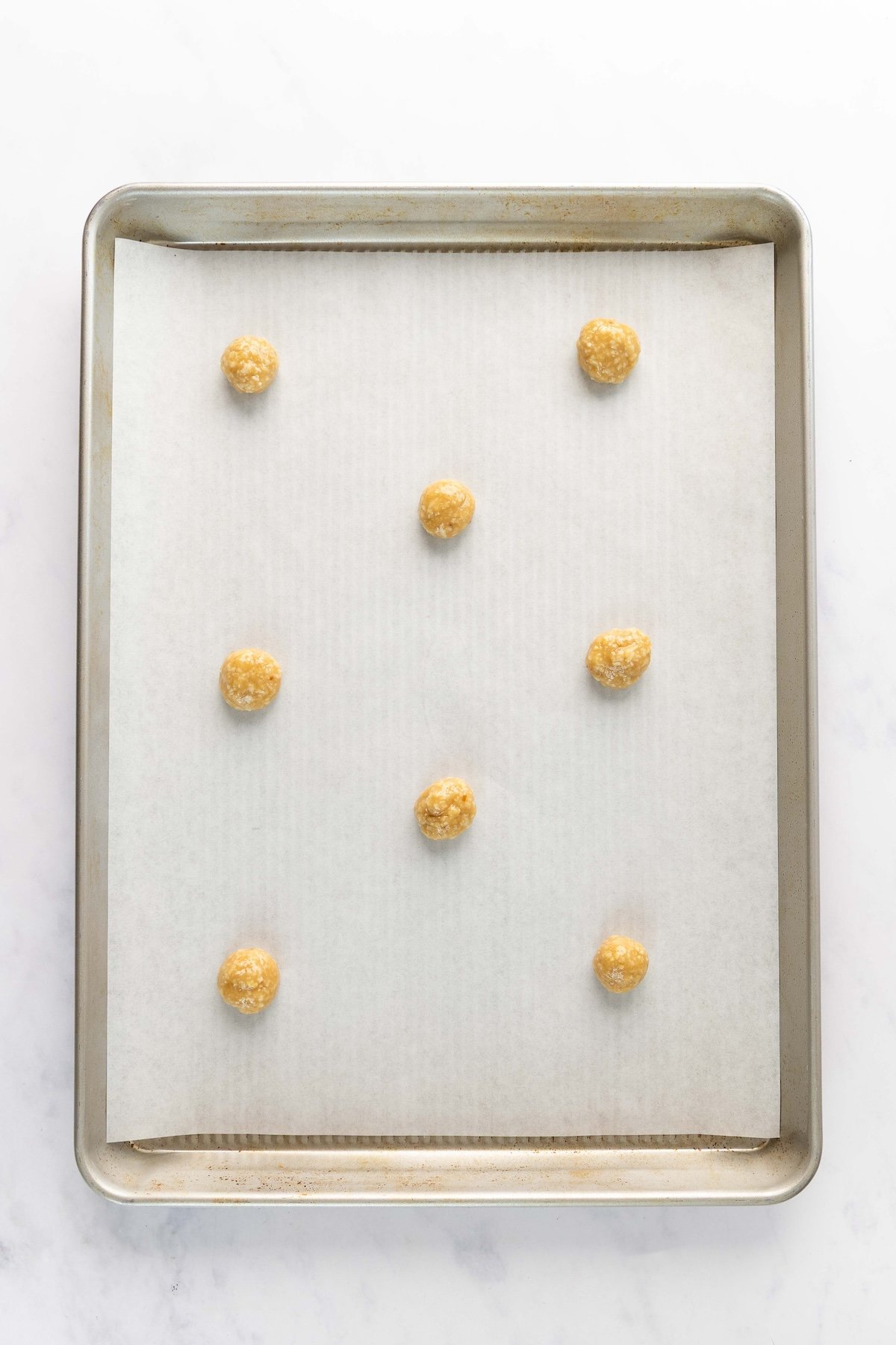 parchment-lined baking sheet with small dough balls