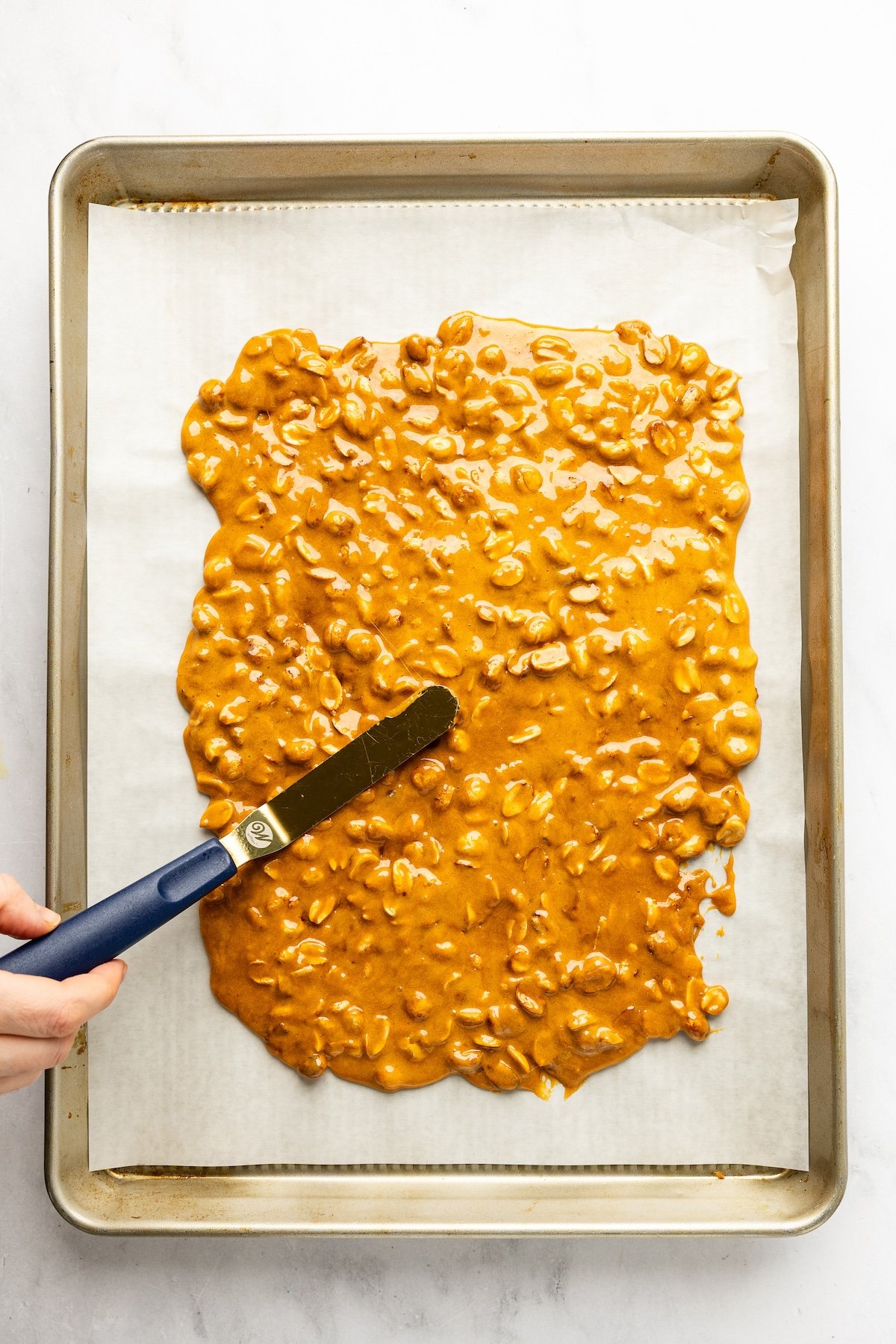 peanut brittle spread evenly on parchment-lined baking sheet