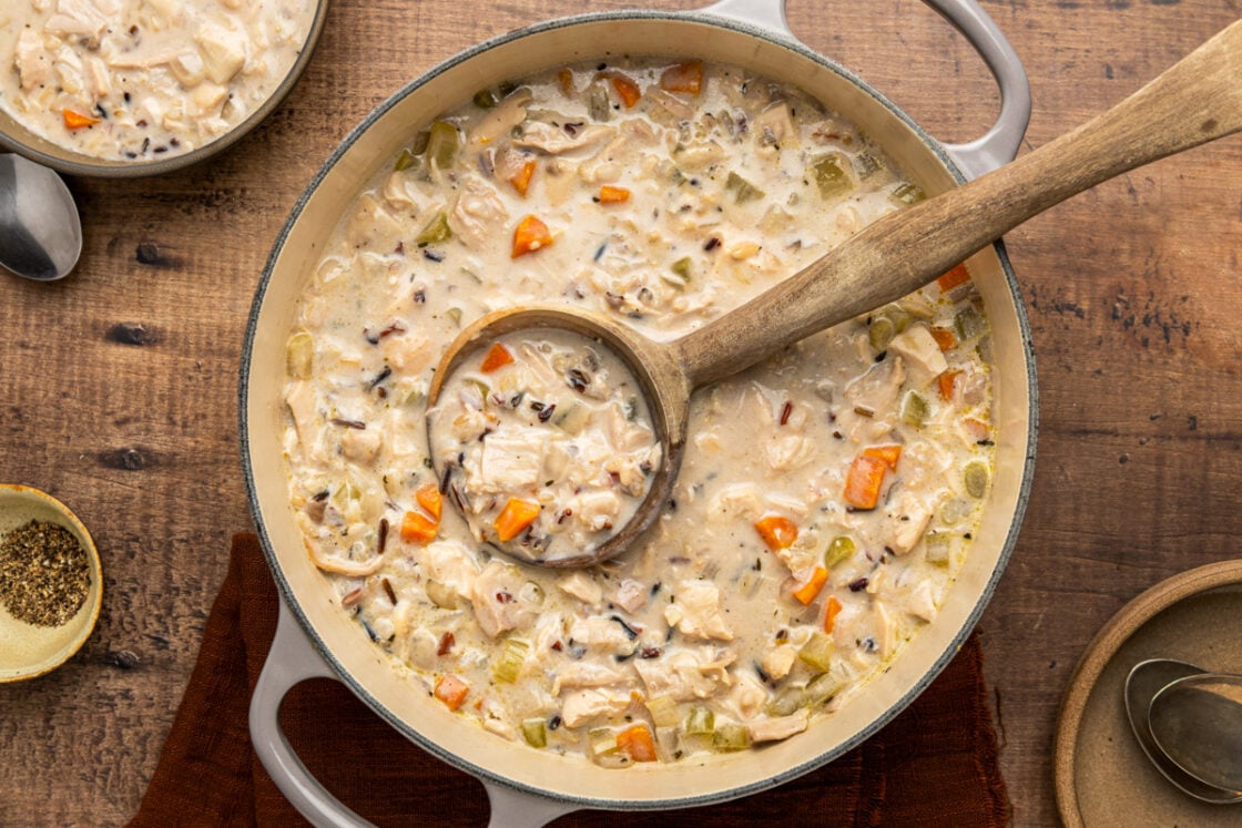chicken and wild rice soup in Dutch oven with wooden spoon