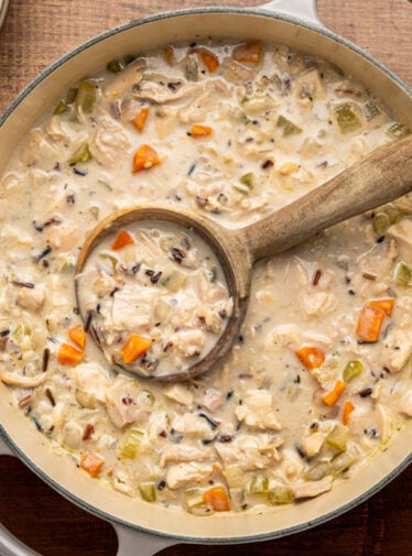 chicken and wild rice soup in Dutch oven with wooden spoon