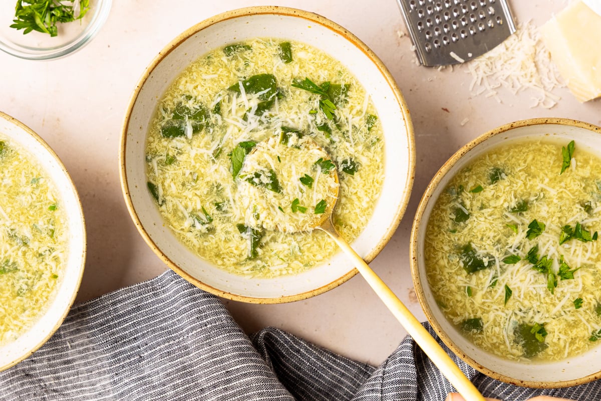 stracciatella soup in bowls with Parmesan cheese and parsley