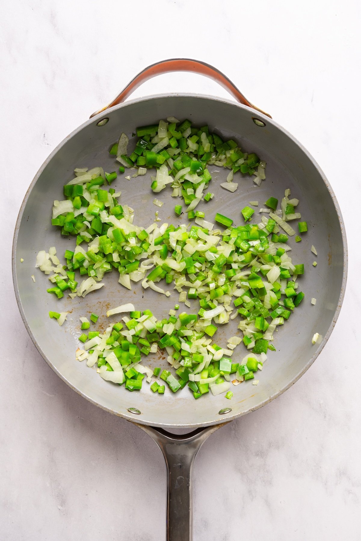 large skillet with onion and green pepper cooking