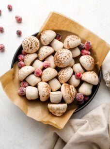 parchment lined bowl with meringue mushrooms scattered with sugared cranberries