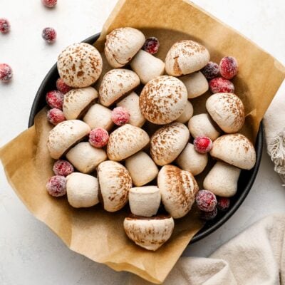 parchment lined bowl with meringue mushrooms scattered with sugared cranberries