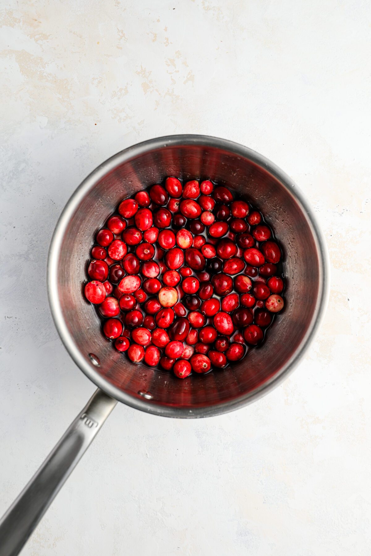 small saucepan with fresh cranberries added to sugar/water mixture