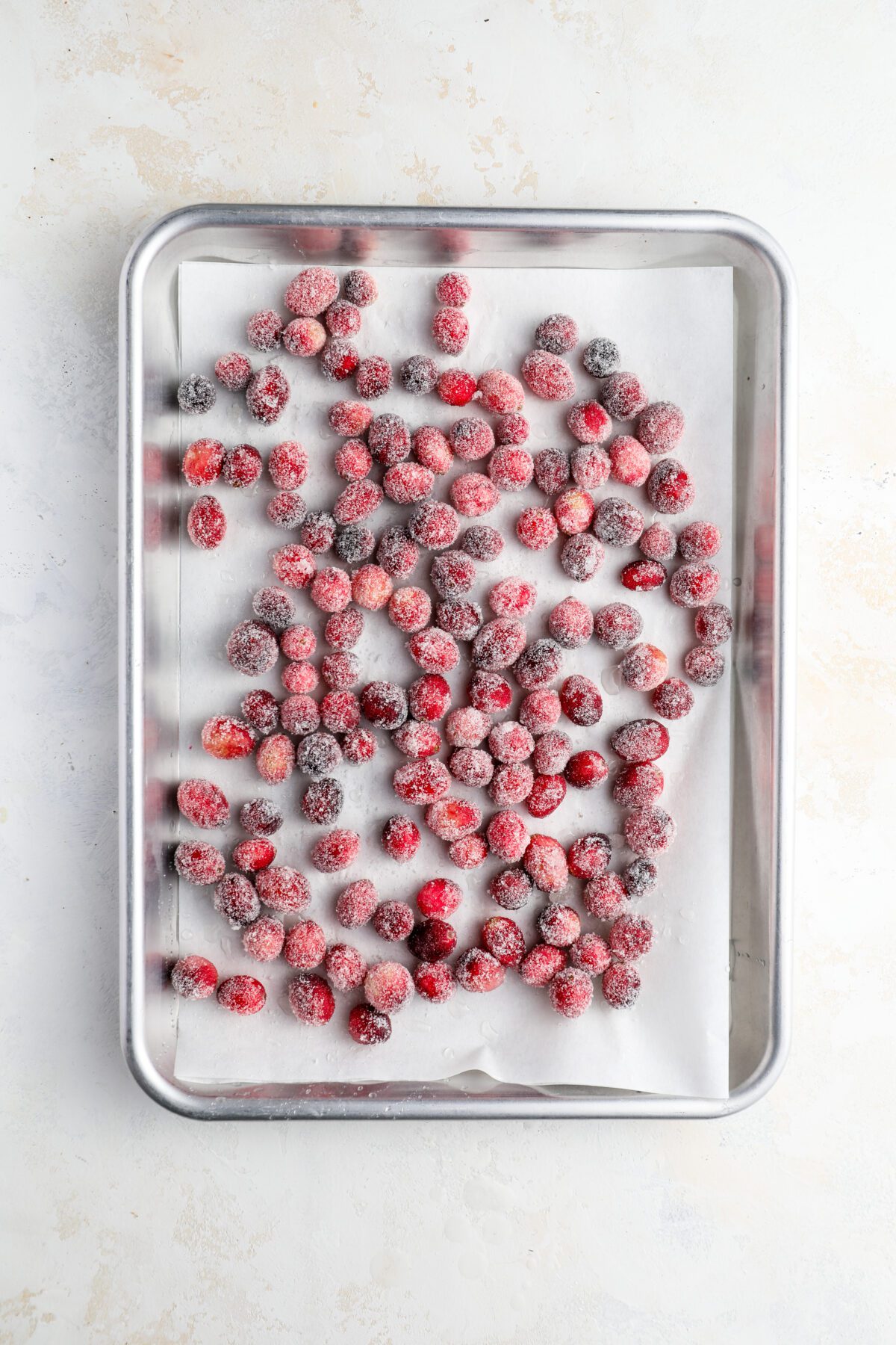 sugar-coated cranberries drying on parchment-covered sheet pan