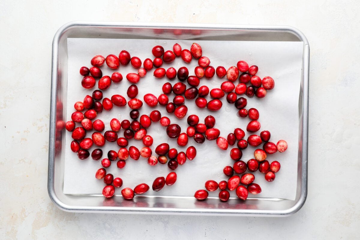 syrup coated cranberries drying on parchment-covered sheet pan
