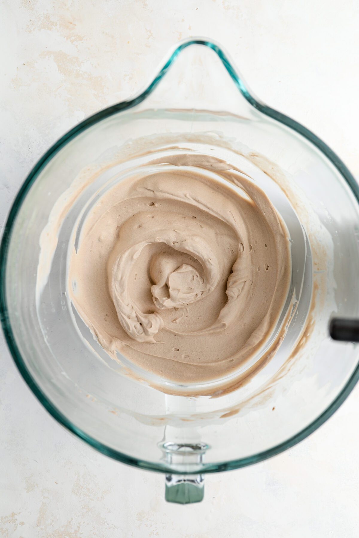 mixing bowl with cream cheese whipped with sugar, cocoa powder, cream, vanilla, and rum