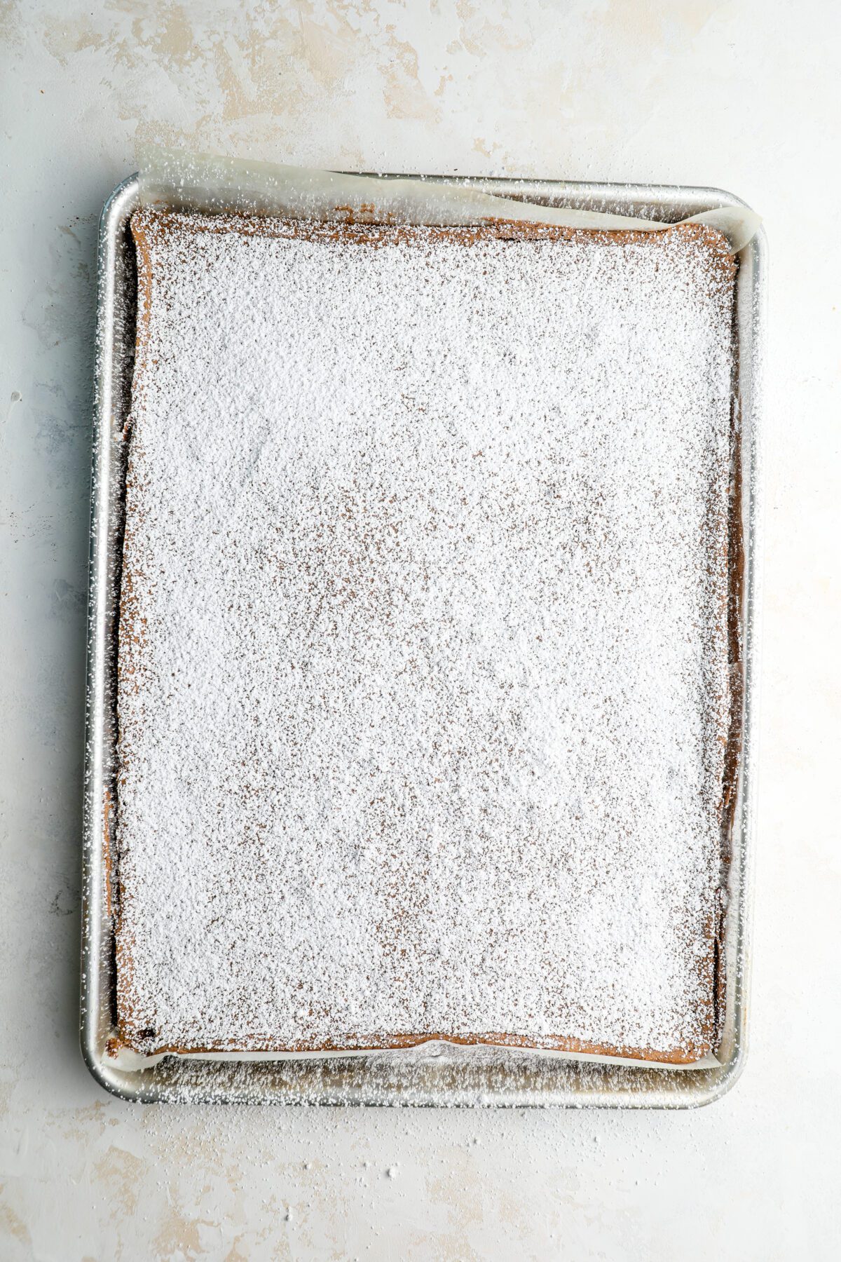jelly roll pan with cake generously dusted with confectioners' sugar