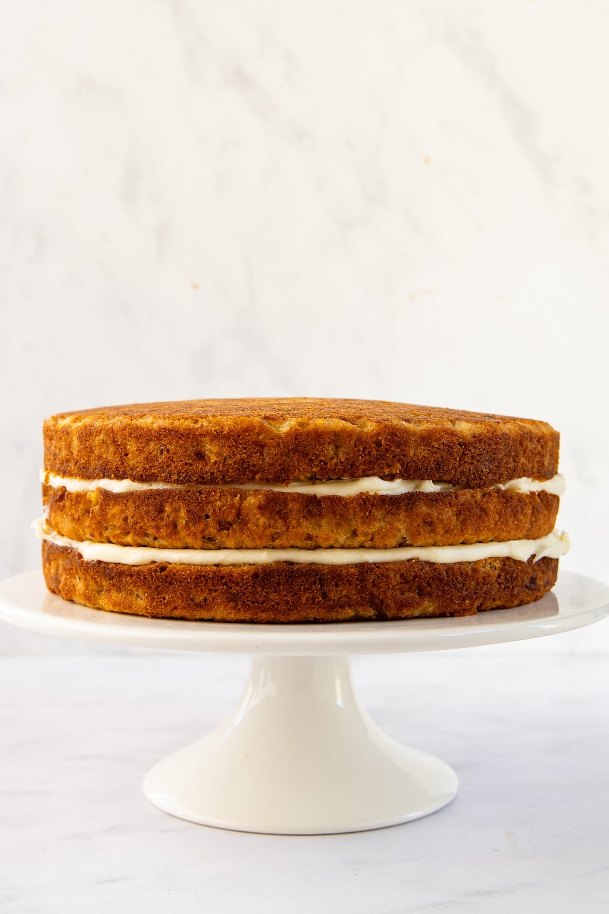white cake stand with three cake layers without frosting on sides or top