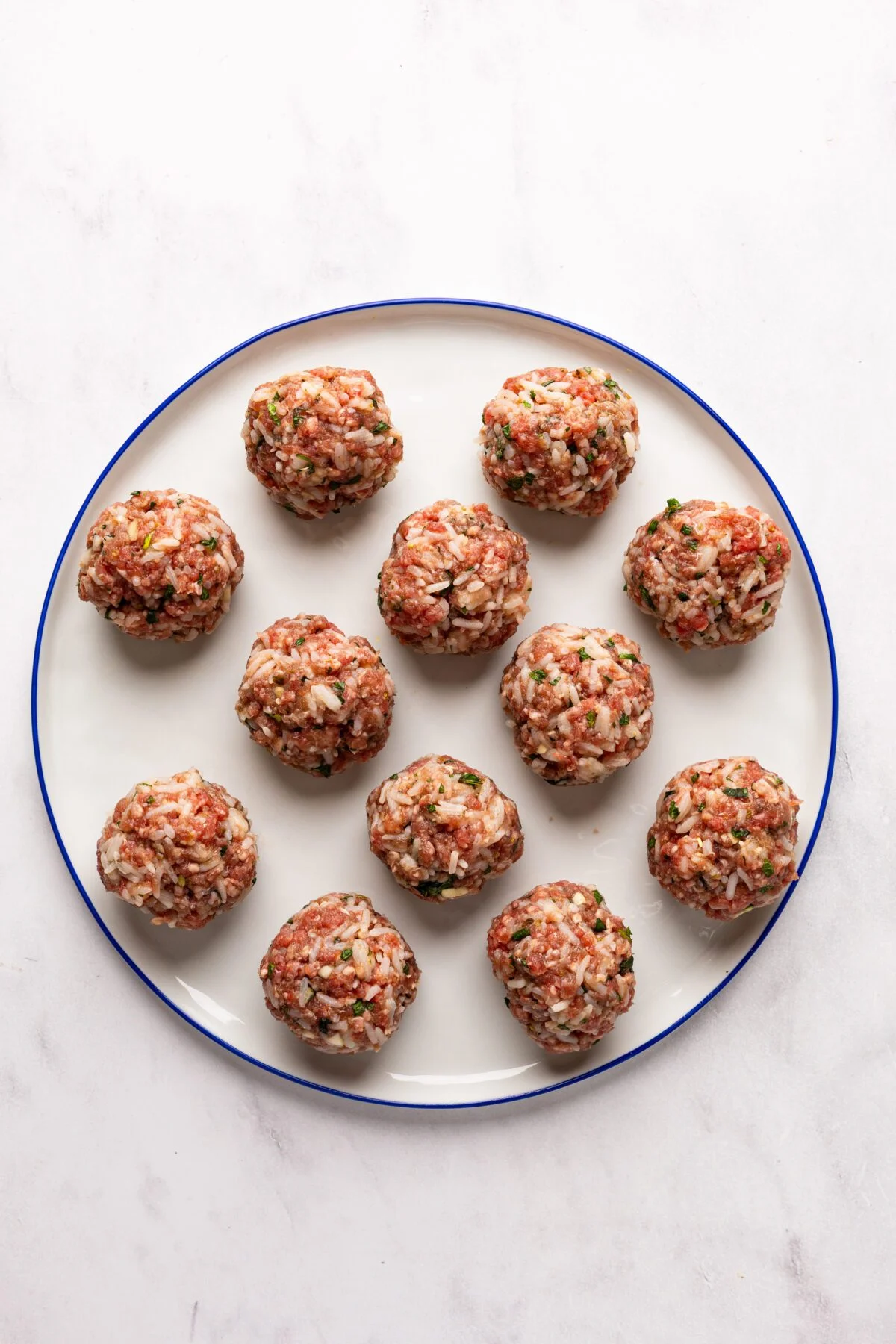 white plate with 12 uncooked meatballs