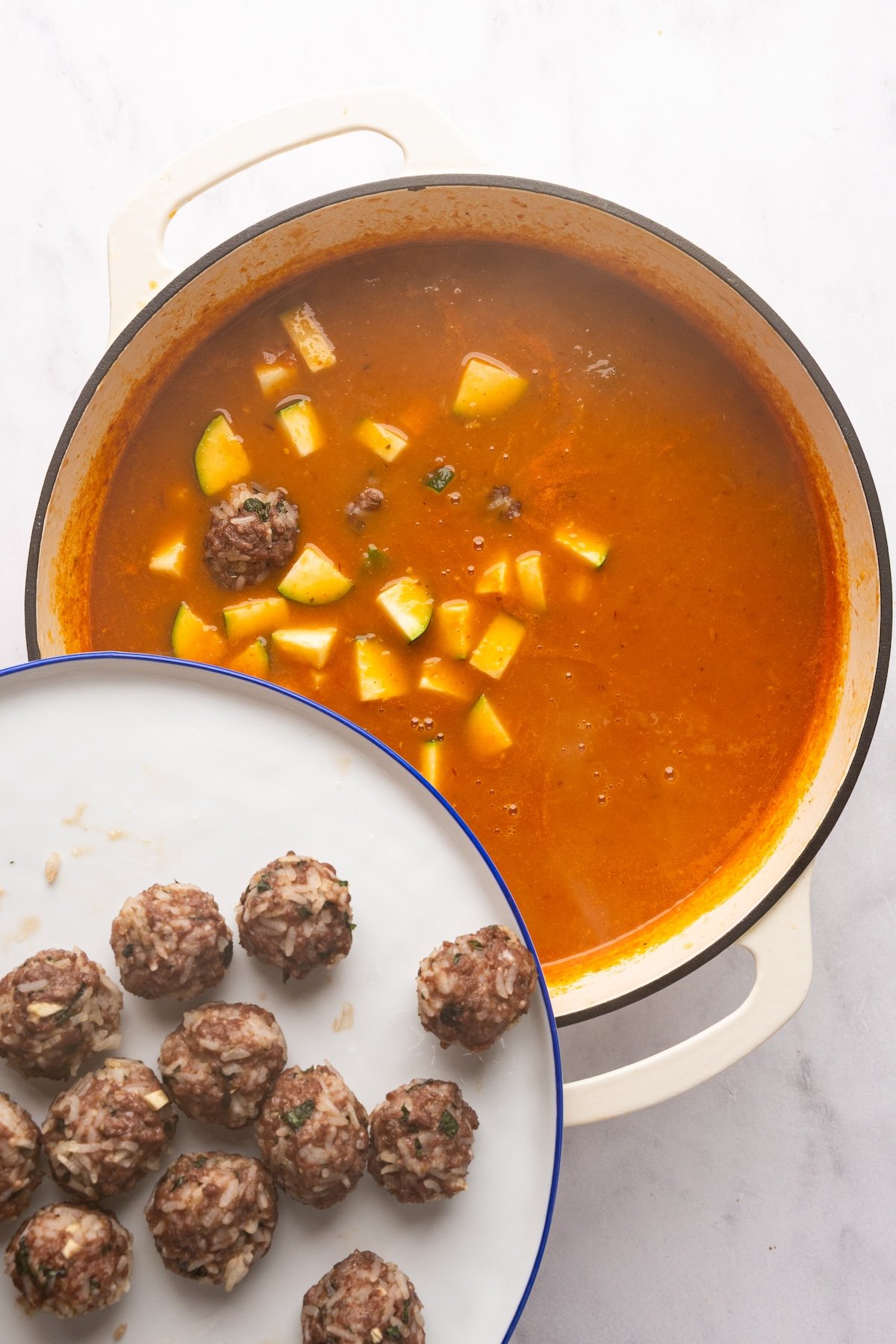 adding meatballs to dutch oven with albondigas soup