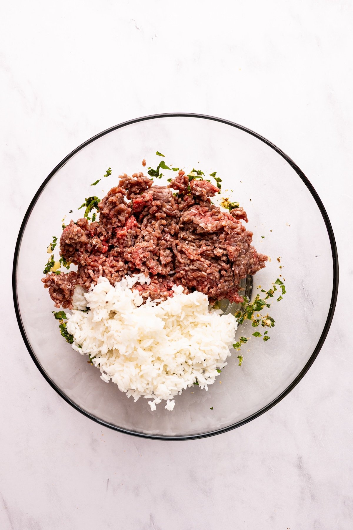 large bowl with meatloaf mix and cooked rice piled on top of egg and herb mixture