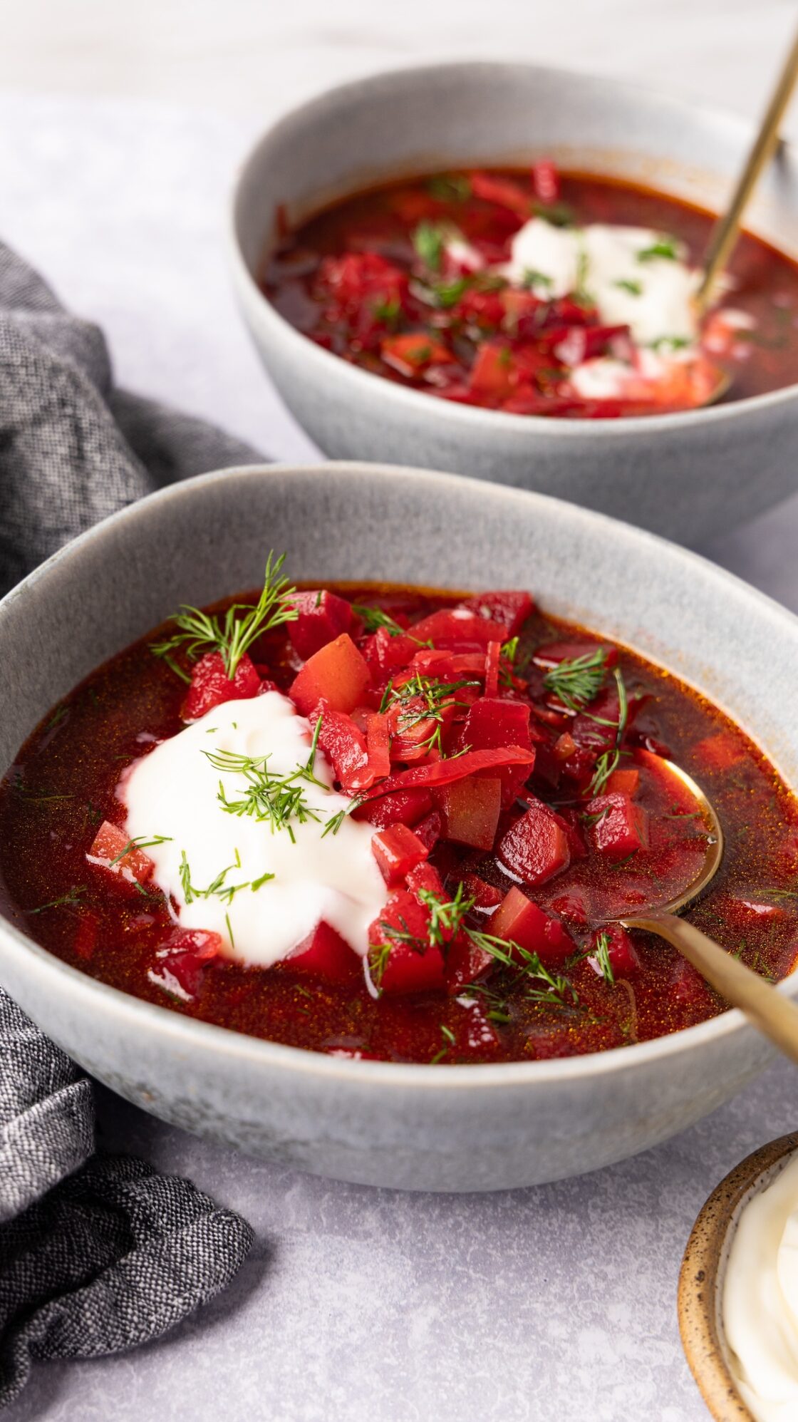 2 bowls of borscht topped with sour cream and fresh dill