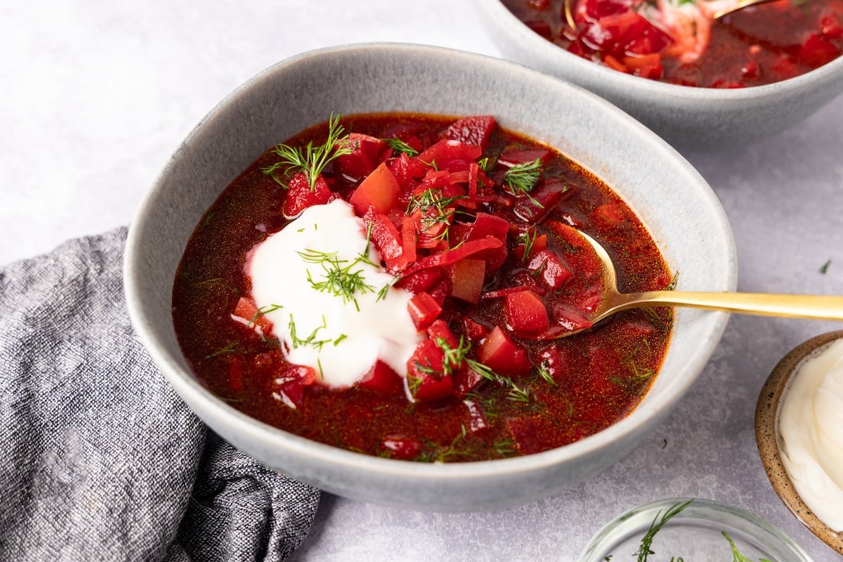bowl of borscht topped with sour cream and dill