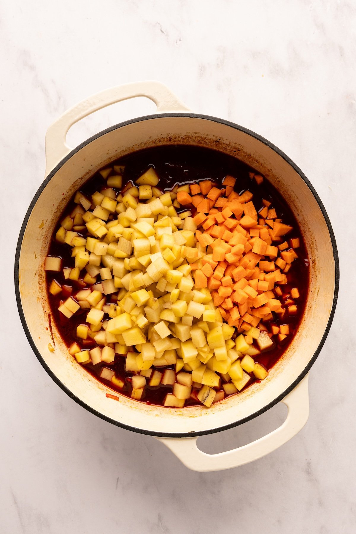 adding potatoes and carrots to the borscht