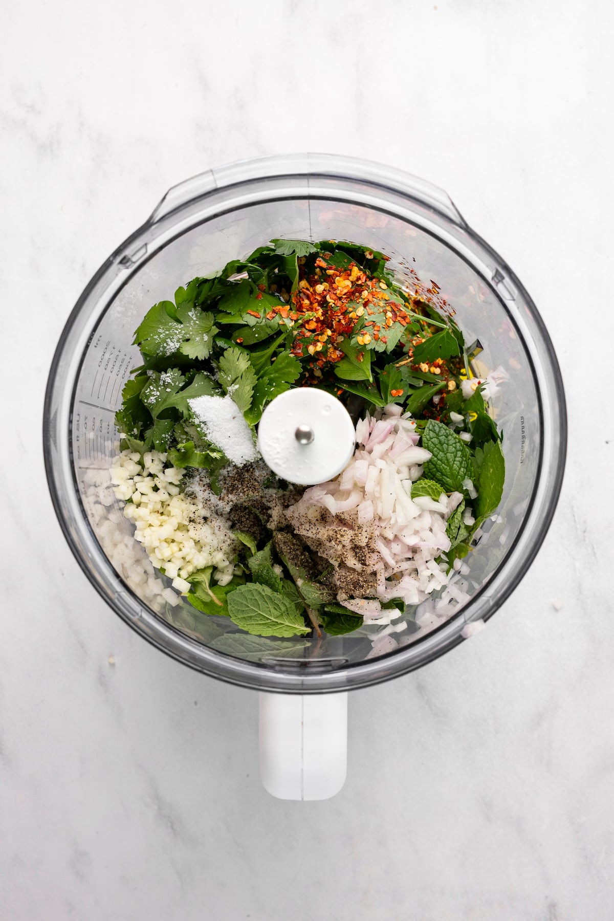 olive oil, vinegar, lemon juice, garlic, shallot, salt, pepper, red pepper flakes, parsley, cilantro, and mint in bowl of food processor 