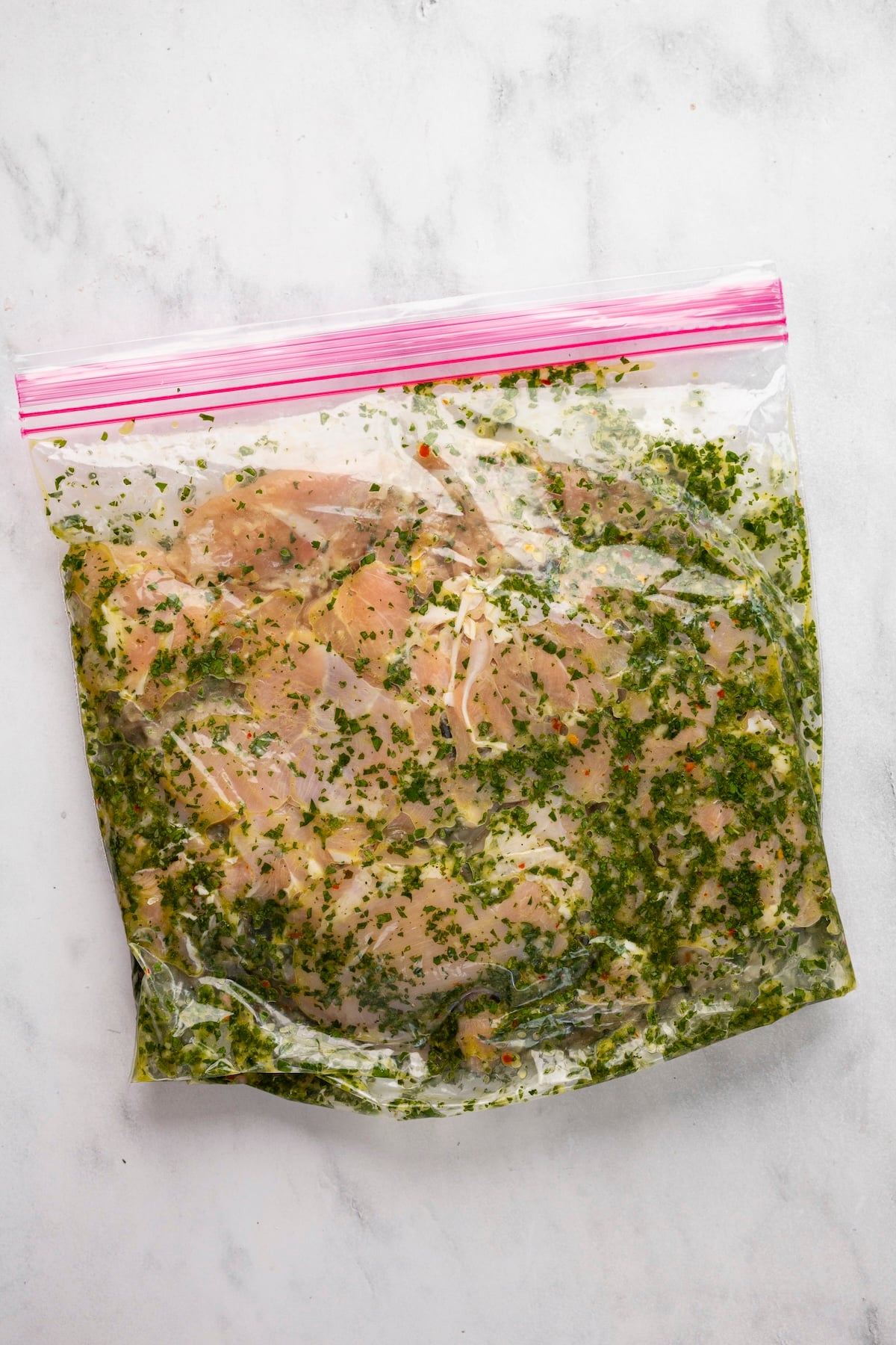 zip-top bag with chicken thighs and chimichurri marinade