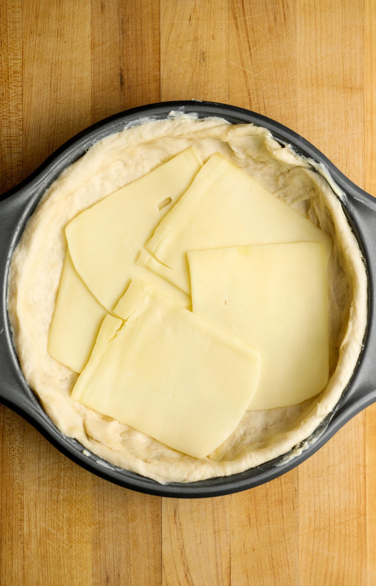 9-inch baking pan with slice mozzarella arranged over pizza dough