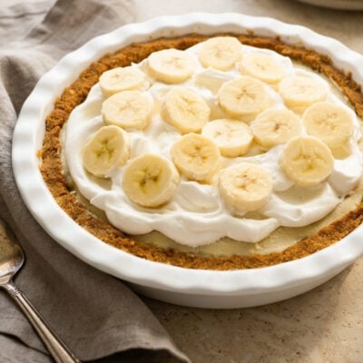 banana cream pie with a linen napkin and stack of plates