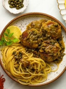Chicken piccata meatballs with pasta and a glass of red wine.